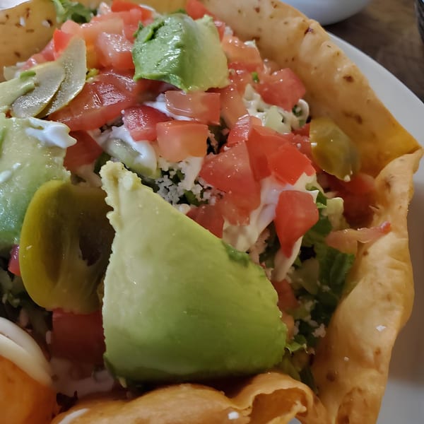 Close-up of a taco salad from Taqueria Jessy's, with avocado, tomatoes, and sour cream.