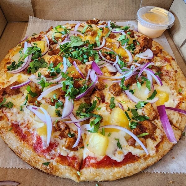 Taqueria Jessy's Mexican pizza with pineapple, red onion, cilantro, and a side of sauce.